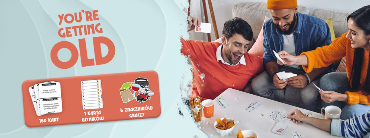 Grupa dorosłych gra w imprezową grę karcianą You’re Getting Old – międzypokoleniową zabawę pełną humoru i wspomnień, idealną na spotkania z przyjaciółmi i rodziną.