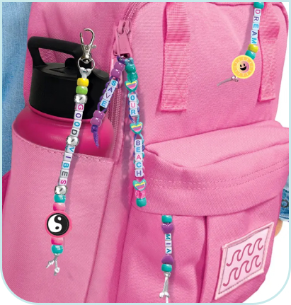 Kolorowe bransoletki z koralików wykonane zestawem Style 4 Ever Projekt Glam – Bransoletki Przyjaźni, przypięte do różowego plecaka jako ozdobne zawieszki.