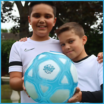 Dwóch chłopców w sportowych strojach trzyma niebiesko-białą interaktywną piłkę Counter Ball Smart Ball do kapkowania na świeżym powietrzu.