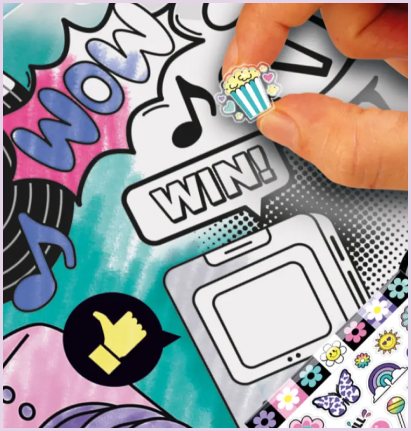 Dłoń naklejająca kolorową naklejkę z popcornem na ozdobną rolkę z zestawu Style 4 Ever Projekt Deko – Rolka do Dekorowania, z widocznymi napisami „WOW” i „WIN”.