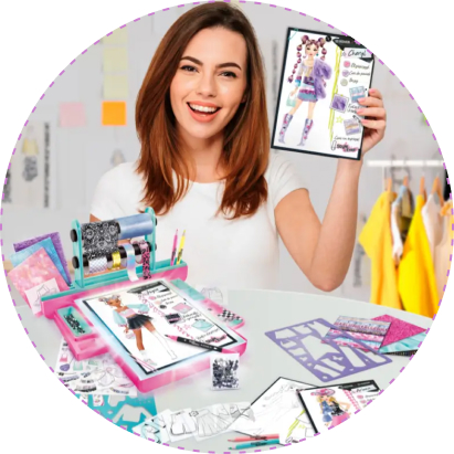 Dziewczyna prezentuje swój projekt modowy wykonany w zestawie Projekt Moda Style 4 Ever – Pracownia z podświetlaną tablicą, otoczona szablonami, arkuszami i kolorowymi materiałami do tworzenia stylizacji.