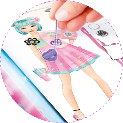 Zbliżenie na projekt modowy z zestawu Projekt Moda Style 4 Ever – Pracownia z podświetlaną tablicą, przedstawiający modelkę w różowej sukience, do której uczestnik dodaje naklejkę torebki jako modny dodatek.